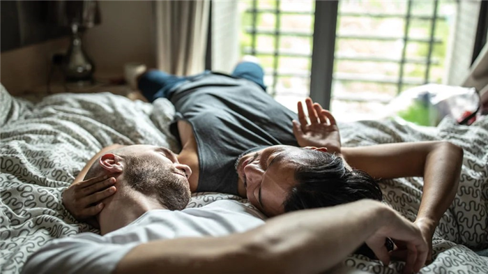 two men lying in bed and being affectionate, but not having sex because they are currently in the refractory period