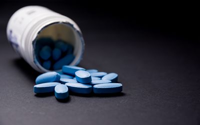 Blue pills coming out of white pill container