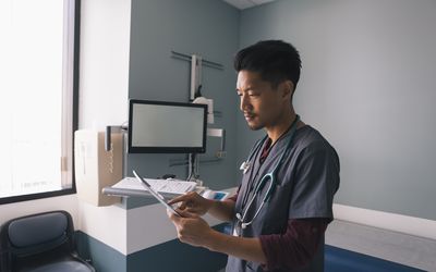 A healthcare provider checks a tablet in an exam room