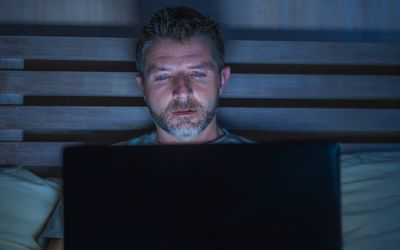 Man with laptop computer in bed